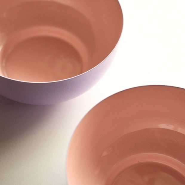 Two pink metal fruit bowls on a light gray surface